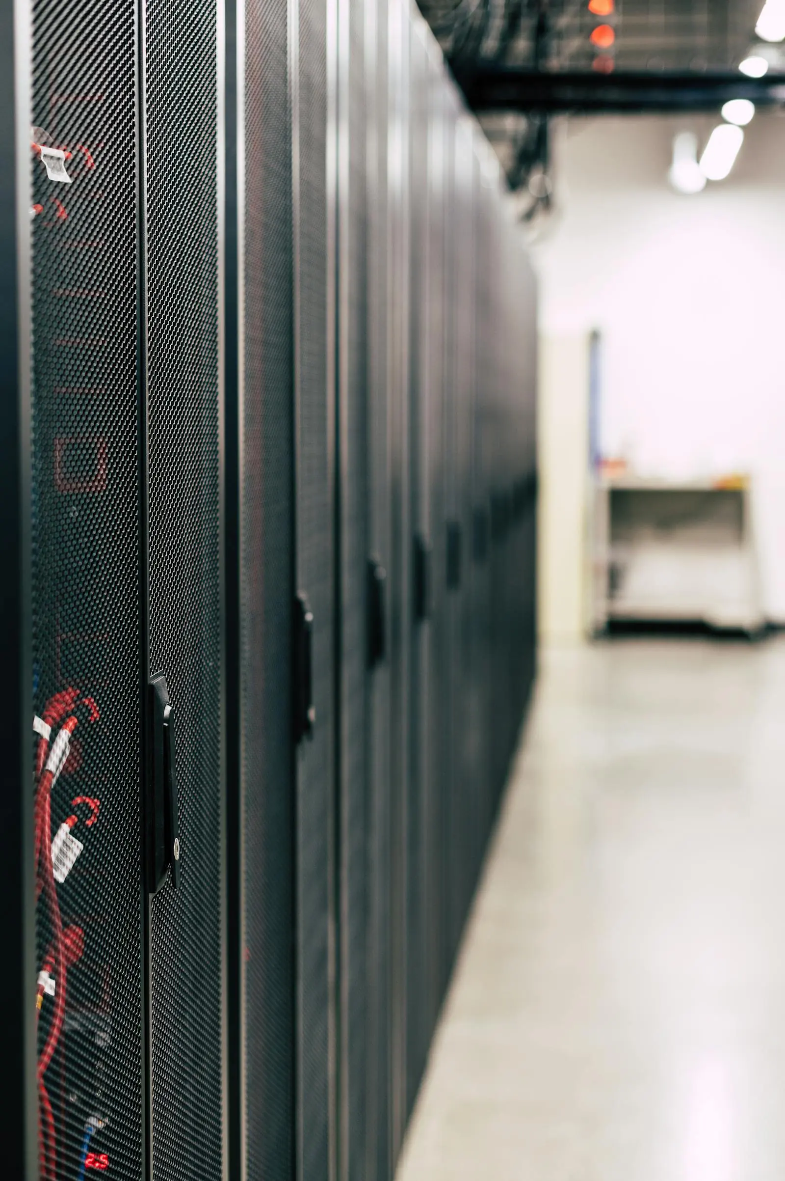 Close view along a row of black server cabinets in a brightly lit data center