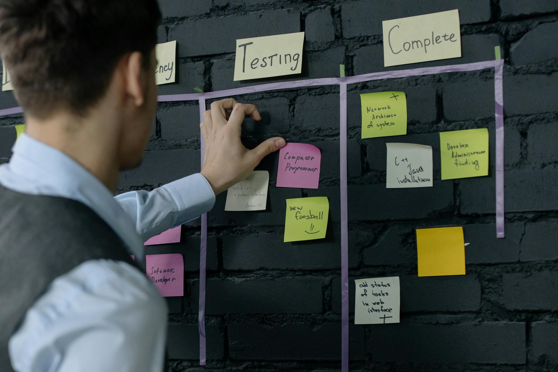 Project manager organizing workflow tasks on a wall with sticky notes in a modern office